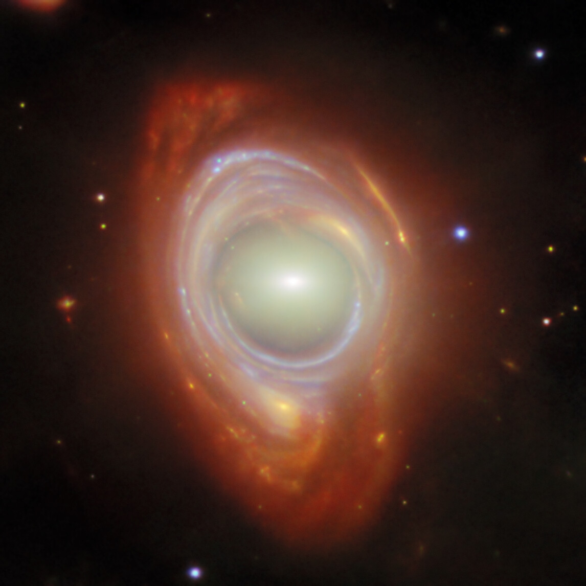 En blåvit Einsteinring runt en ljus galax. Ringen är ljus från en galax längre bakom, böjt av gravitationen hos galaxen i mitten.